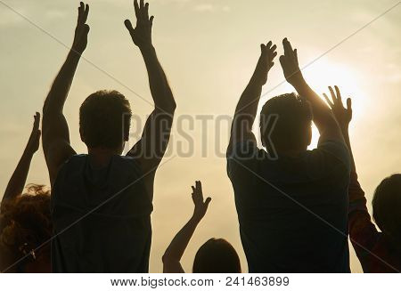 Back View People Applauding. Silhouette Clapping People Against Evening Sun Background.