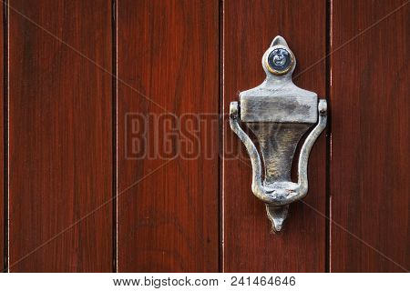 Old Metal Silver Door Knocker With An Eyehole On A Rough Wooden Background
