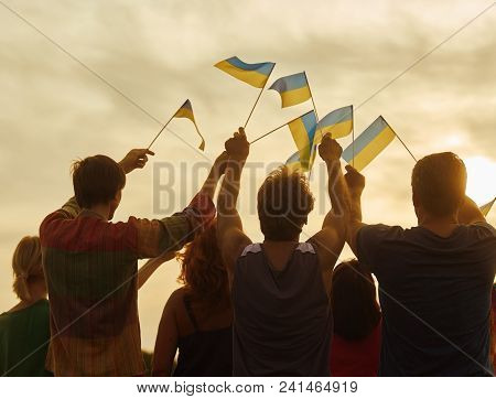 Back View, Silhouette Of Ukrainian People With Flags. Patriotic Family Against Sunset Background.