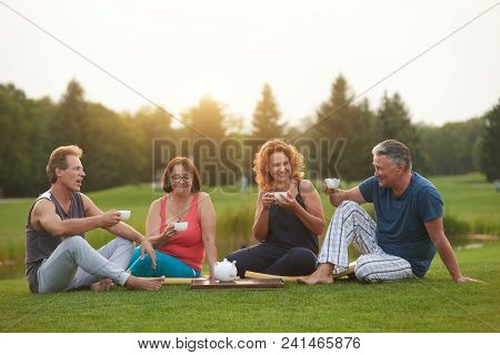 Mature People Having Tea Coversation. Resting Outdoor In The Summer Park.