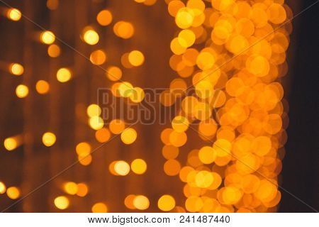 Many Blurred Small Electric Bulbs On A Wall. Yellow Blurred Lights. Wall Of Christmas Lights