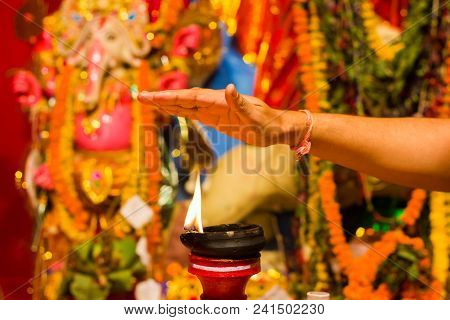 A Hand Taking Heat Of The Flame As Blessing From A Lit Clay Lamp On Top Of A Clay Stand Or Worship I