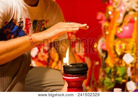 A Hand Taking Heat Of The Flame As Blessing From A Lit Clay Lamp On Top Of A Clay Stand Or Worship I