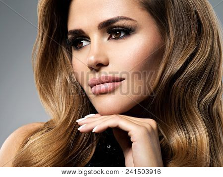 Closeup portrait with a pretty female face. Beautiful young woman with long brown hair.  Fashion model with plump lips  posing at studio.