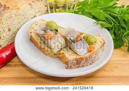 Open Sandwich Made Of Brown Sprouted Bread, Slices Of Fillet Of Pickled Atlantic Herring And Green O