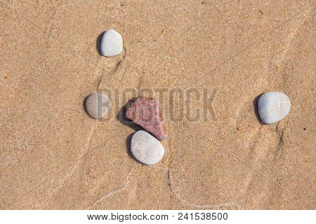 Beautiful Smooth Sea Stones In The Sands Of The Beach. Closeup Photo Of Stone Textures And Shapes.