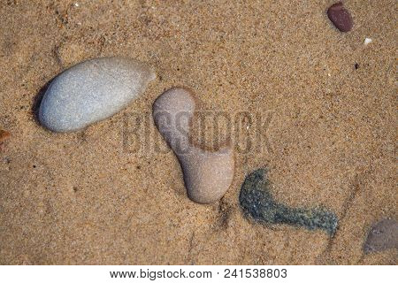 Beautiful Smooth Sea Stones In The Sands Of The Beach. Closeup Photo Of Stone Textures And Shapes.