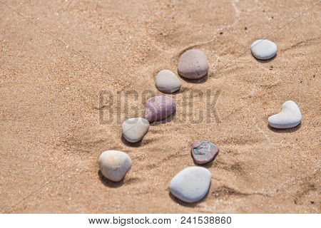 Beautiful Smooth Sea Stones In The Sands Of The Beach. Closeup Photo Of Stone Textures And Shapes.