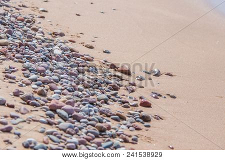 Beautiful Smooth Sea Stones In The Sands Of The Beach. Closeup Photo Of Stone Textures And Shapes.