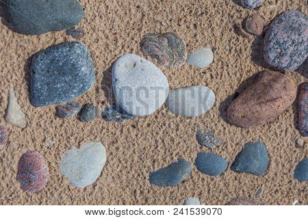 Beautiful Smooth Sea Stones In The Sands Of The Beach. Closeup Photo Of Stone Textures And Shapes.