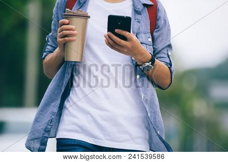 woman walking with coffee themo cup in hand on city street