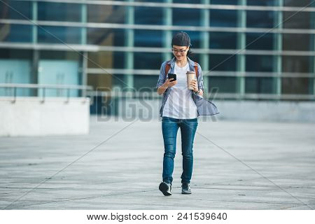 Woman Walking With Coffee Themo Cup In Hand On City Street