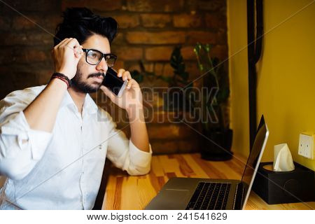 Teenage Indian Male Using Phone At Cafe