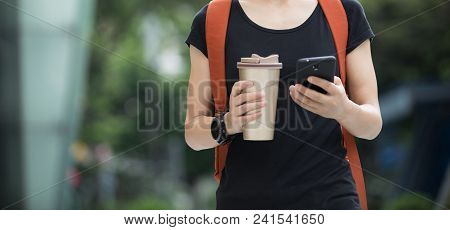 Walking With Coffee Themo Cup In Hand And Use Cellphone On City Street
