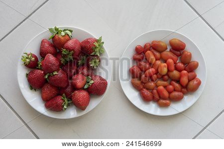 Fresh Strawberries And Fresh Small Tomatoes Served On A White Plate And Isolated In Grey Natural Cer