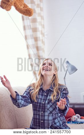 We Are Happy To Regain Our Childhood. Happy Teenage Girl Playing With Teddy Bear Sitting On Sofa. We