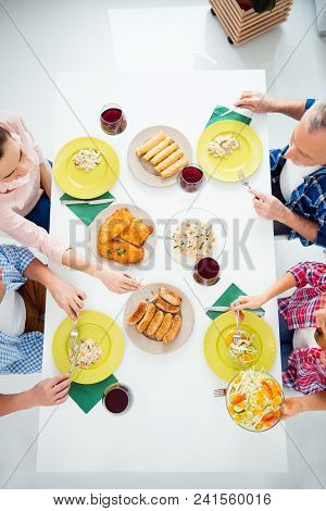 Top View Cropped Portrait Of Festive Relatives Imposing Food In Plates, Eating With Knife And Fork, 