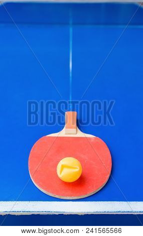 Old Pingpong Racket And A Dented Ball On A Blue Pingpong Table