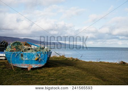 An Unidentified Blue Wooden Fishing Boat Full Of Fishing Nets On The Grass By The Shore In Brora, Sc