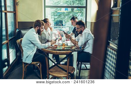 Young Cheerful People Smile And Gesture While Relaxing In Pub. Team Job. Photo Young And Mature Busi