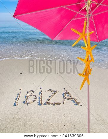 Pink Parasol Yellow Starfish Summer Theme And Ibiza Written In Sand On Beach In Ibiza, Spain