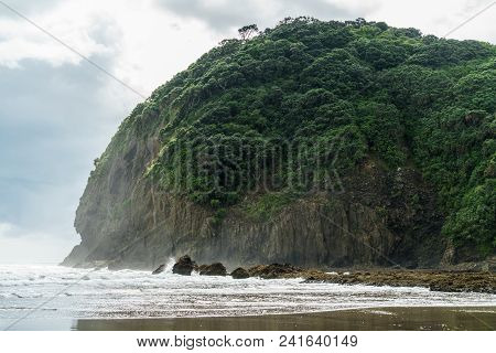 Scenic Shot Of Green Cliff On Ocean Coastline On Cloudy Day, Piha Beach, New Zealand