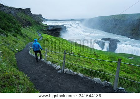 Gullfoss - most beautiful waterfall in Iceland. Golden Ring Tourist Attraction. Man in blue jacket near the cascade. Beauty in nature