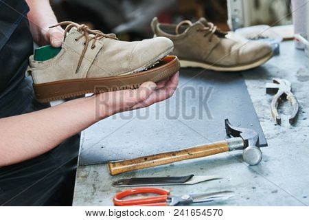 Shoemaker repair shoe. Glueing the sole for male footwear