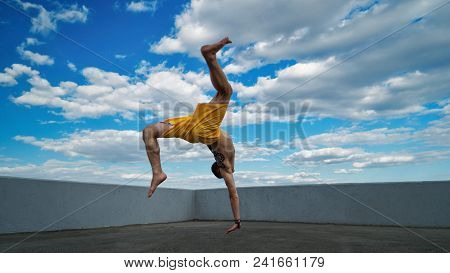 Tricking On Street. Martial Arts. Man Makes Back Flip With Arm Support Barefoot. Shooted From Bottom