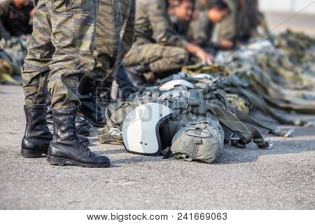 Row Of T-10 Parachute With Helmet And Equipment Standby On Ground Beside Paratrooper In Camouflage U