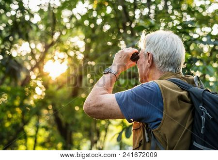 Elderly man watching birds with binoculars