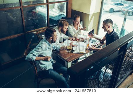 Young Cheerful People Smile And Gesture While Relaxing In Pub. Team Job. Photo Young And Mature Busi