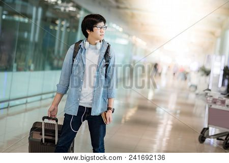 Young Asian Man Dressed In Casual Style Walking With Suitcase Luggage In The International Airport T