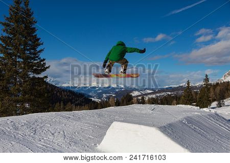 Snowboarder In Action: Jumping In The Mountain Snowpark.