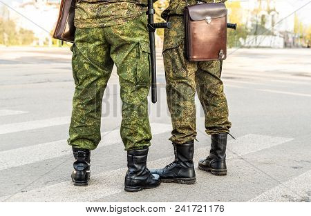 Militaries legs with security truncheons and officers bag, cropped shot.