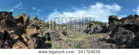 cloudscape on encrusted volcanic rock and Etna Mount panoramic view, Sicily