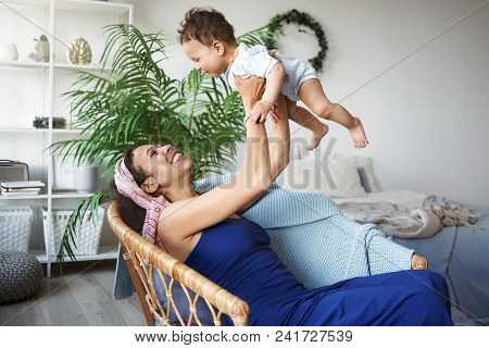 Happy Mom And Child Spending Great Time Together At Home. Attractive Young Hispanic Woman Wearing Bl