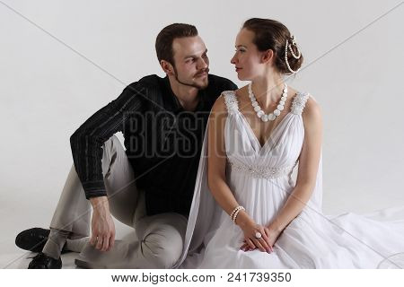 A Guy In A Suit And A Girl In A Greek Dress Look At Each Other