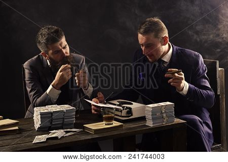 Elegant Man In Suit. Men Sitting At Table With Piles Of Money And Typewriter. Company Engaged In Ill