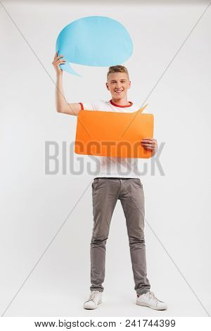 Full length photo of pleased advertiser boy wearing casual t-shirt holding two blank message bubbles copyspace for your text isolated over white background