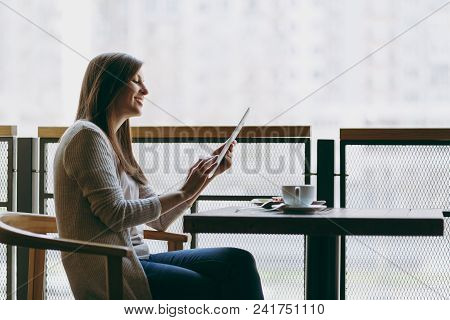 Woman Sitting Alone Near Big Window In Coffee Shop At Table With Cup Of Cappuccino, Cake, Relaxing I