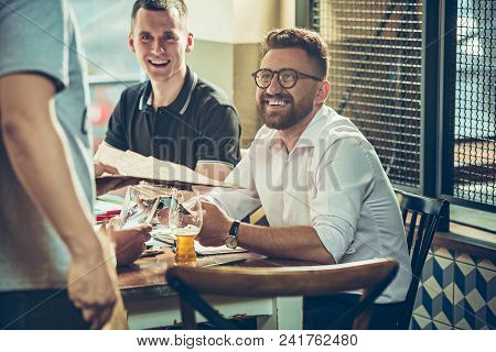 Young Cheerful People Smile And Gesture While Relaxing In Pub. Team Job. Photo Young And Mature Busi