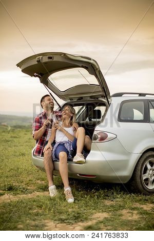 Loving Couple Sitting In The Car Trank