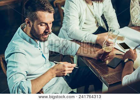 Young Cheerful People Smile And Gesture While Relaxing In Pub. Team Job. Photo Young And Mature Busi