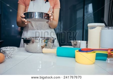 A Woman Sifting Flour Into A Stainless Bowl. Girl Is Sifting Flour To Making The Bakery In Her Kitch