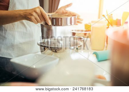 A Woman Sifting Flour Into A Bowl. Girl Is Sifting Flour To Making The Bakery In Her Kitchen On Week