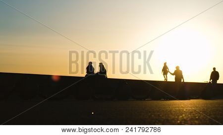 Silhouettes Of The Father With His Daughter Go To The Barber In The Park At Sunset, The Concept Of G