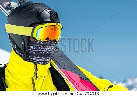 A Lclose-up Portrait Of A Skier In A Protective Helmet And Glasses Is A Mask And Scarf With Skis On 