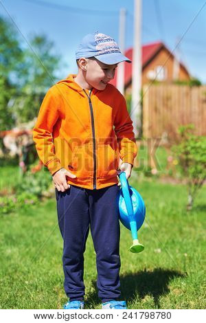 Smiling European Boy With Water Can On A Croft.