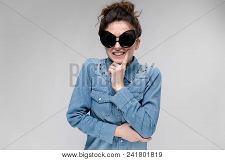 Young Girl In Black Cat Glasses On A Gray Background. Portrait Of A Young Beautiful Girl. Charming G